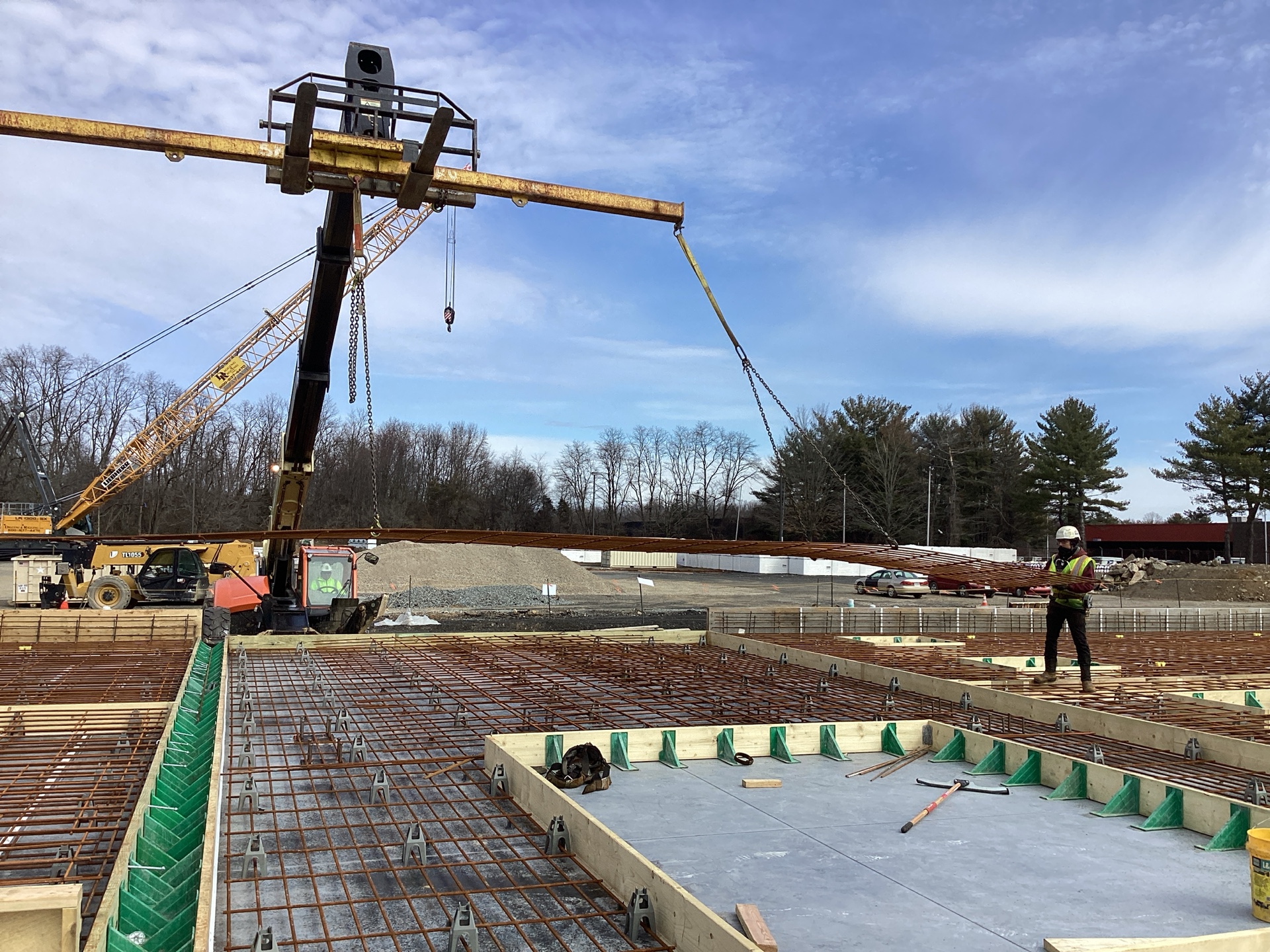 STRUCTURAL WWR BEING PLACED IN TILT-UP WALL PANEL FORMS WITH A SMALL PLACEMENT CREW AND A TELEHANDLER FIT WITH A SPREADER BEAM
